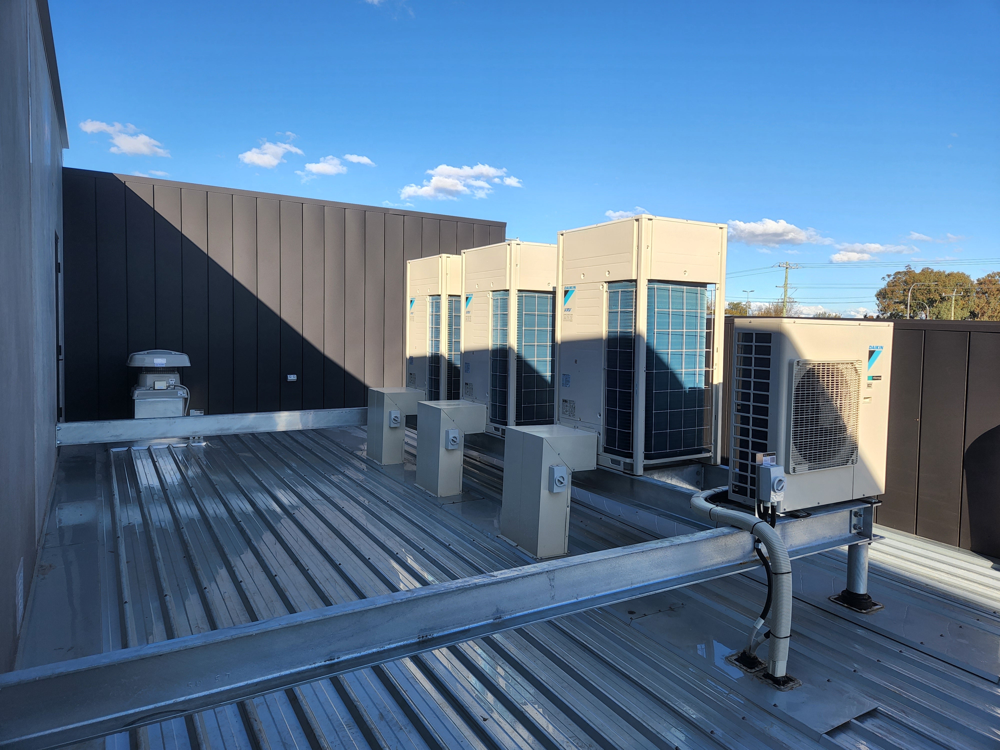 Air conditioning units on a rooftop with a clear blue sky.