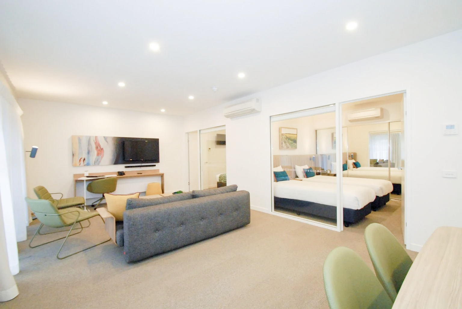 Modern living room with gray sofa, TV, and chairs.