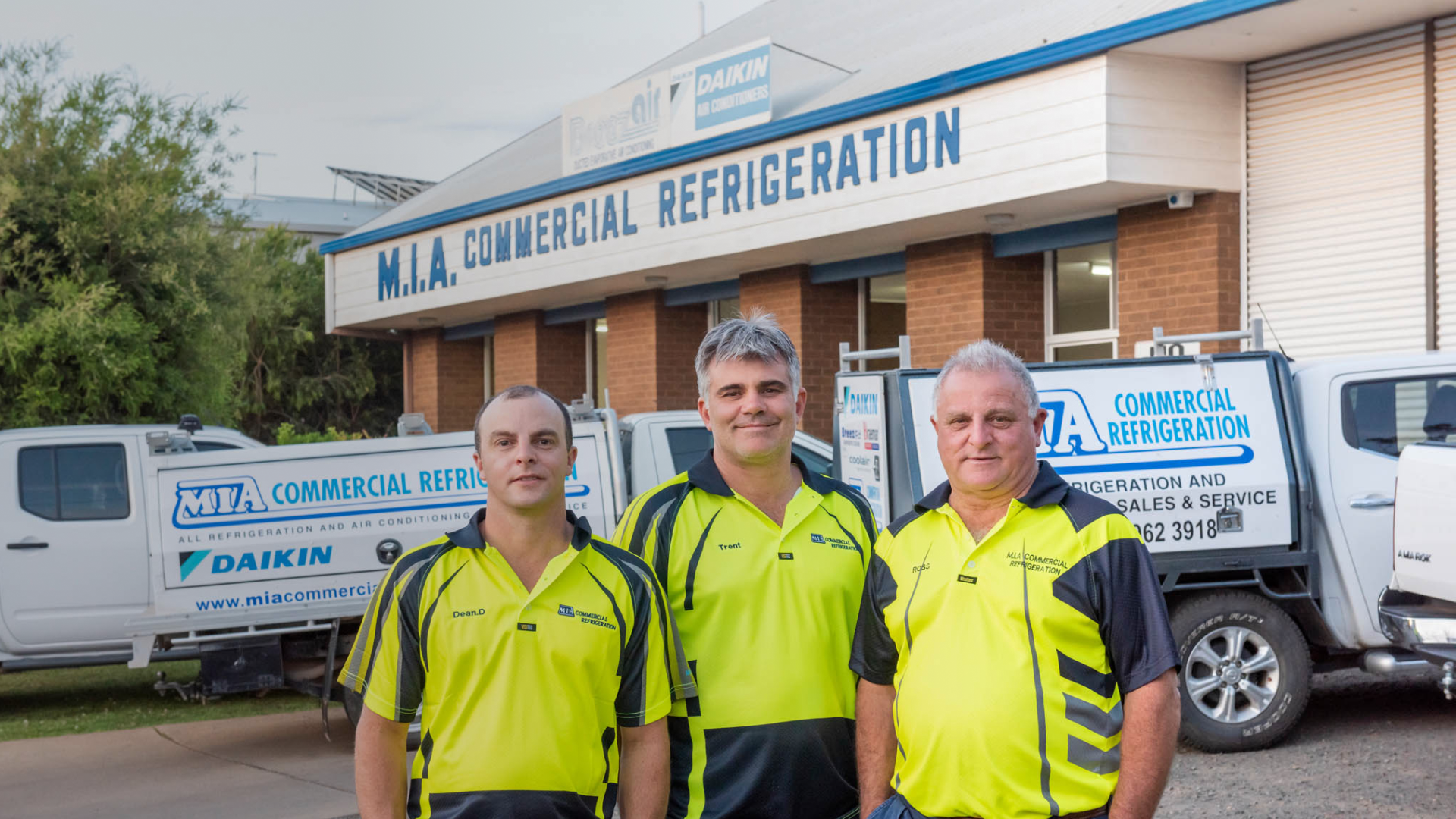 Ross, Dean, and Trent – commercial refrigeration technicians at MIA Commercial Refrigeration Griffith – standing outside workshop with branded service vehicles.