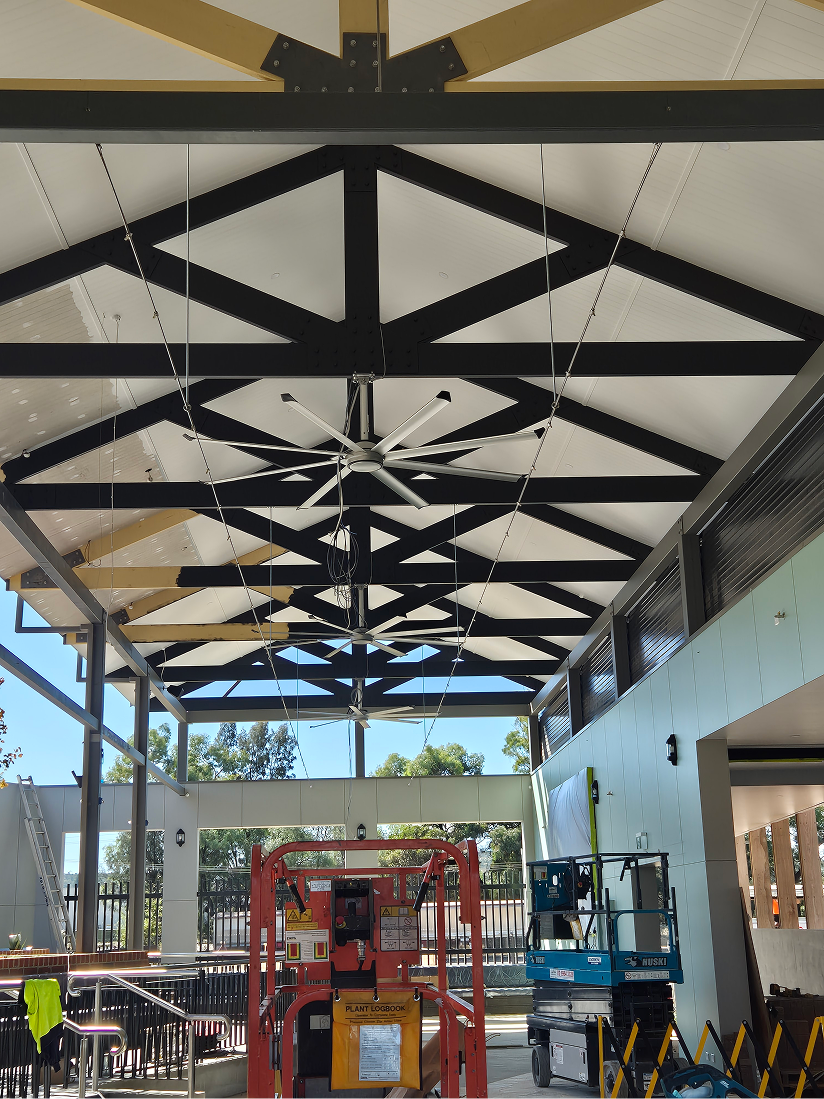Ceiling with geometric black and white design, construction equipment below with big ass fans