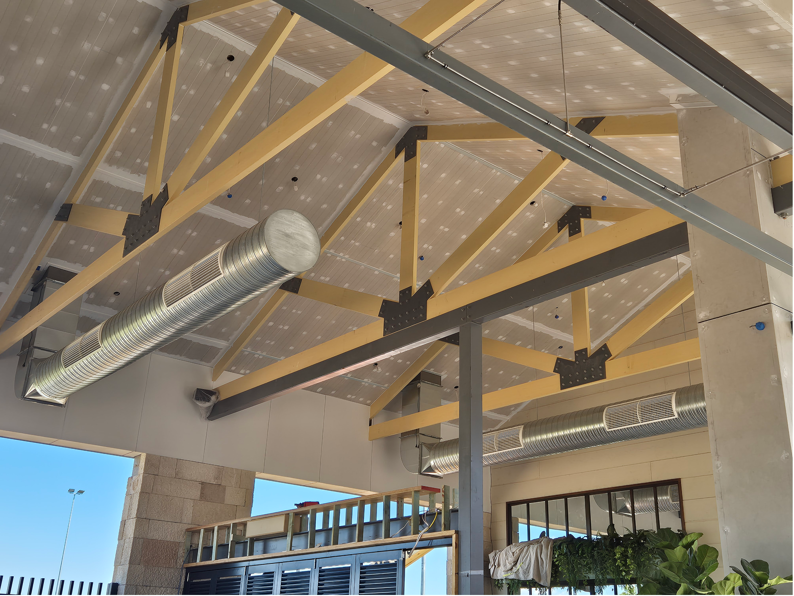 Ceiling with exposed beams and ductwork in a building interior with air conditioning